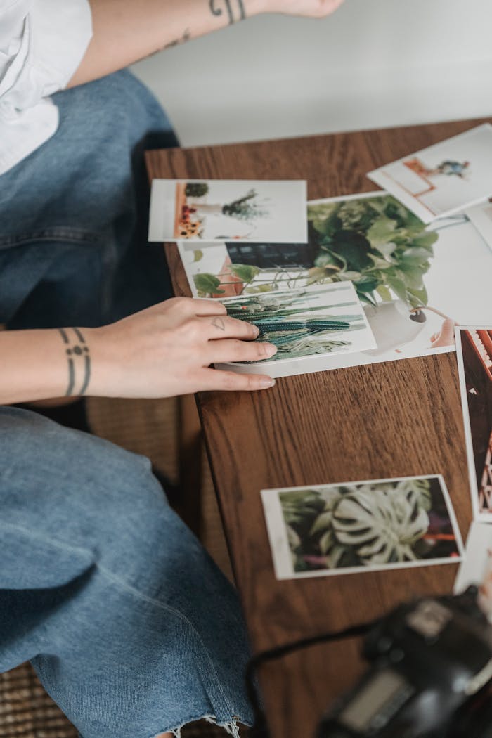Person selecting photography prints at a wooden table in a creative workspace.